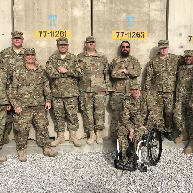 Military servicemen wearing camo and standing posed for a group photo. 